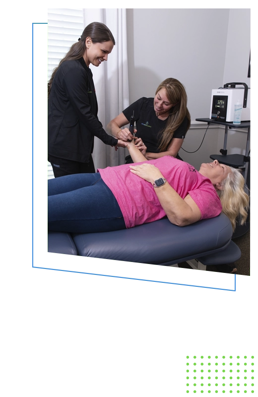 Chiropractic team providing therapeutic arm treatment to a patient on a therapy table.